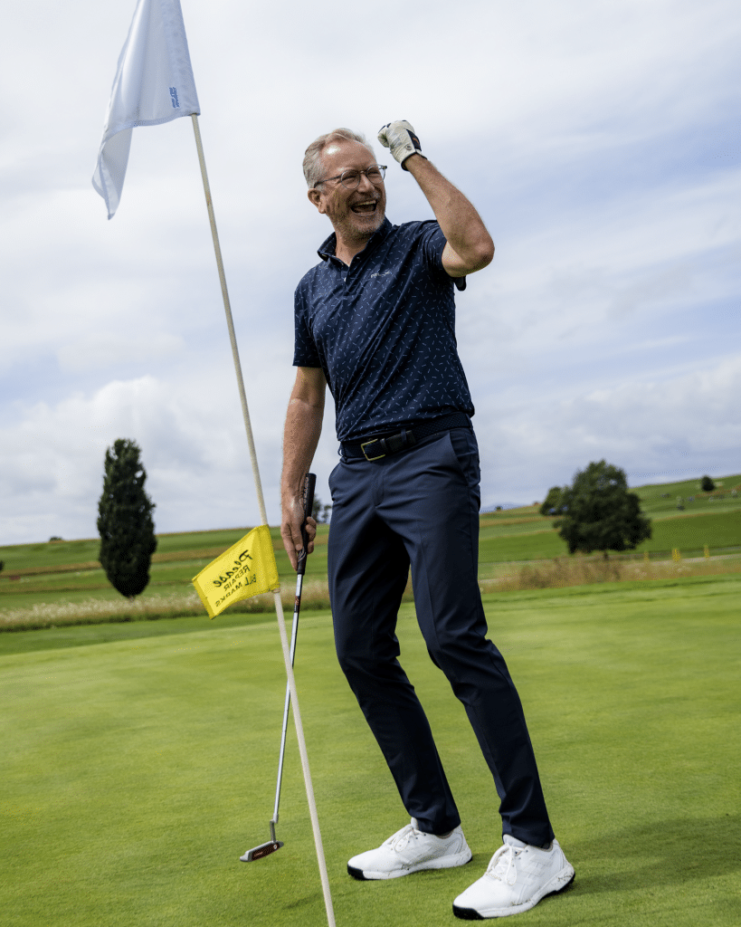 Golfspieler jubelt mit geballter Faust am Grün neben der Fahne nach einem gelungenen Putt beim RT 98 Golfturnier