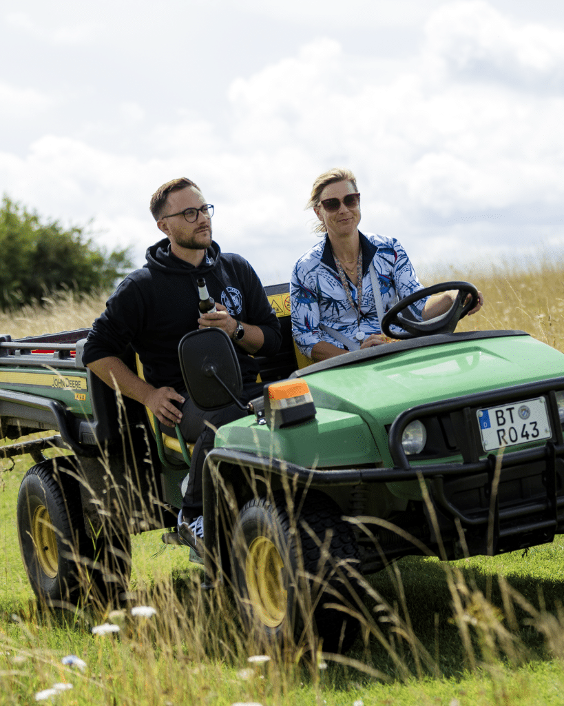 Zwei Helfer sitzen auf einem John Deere Gator am Rand des Golfplatzes und betreuen eine Station beim RT 98 Golfturnier
